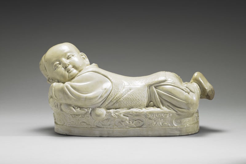 Pillow in the shape of a recumbent child with white glaze